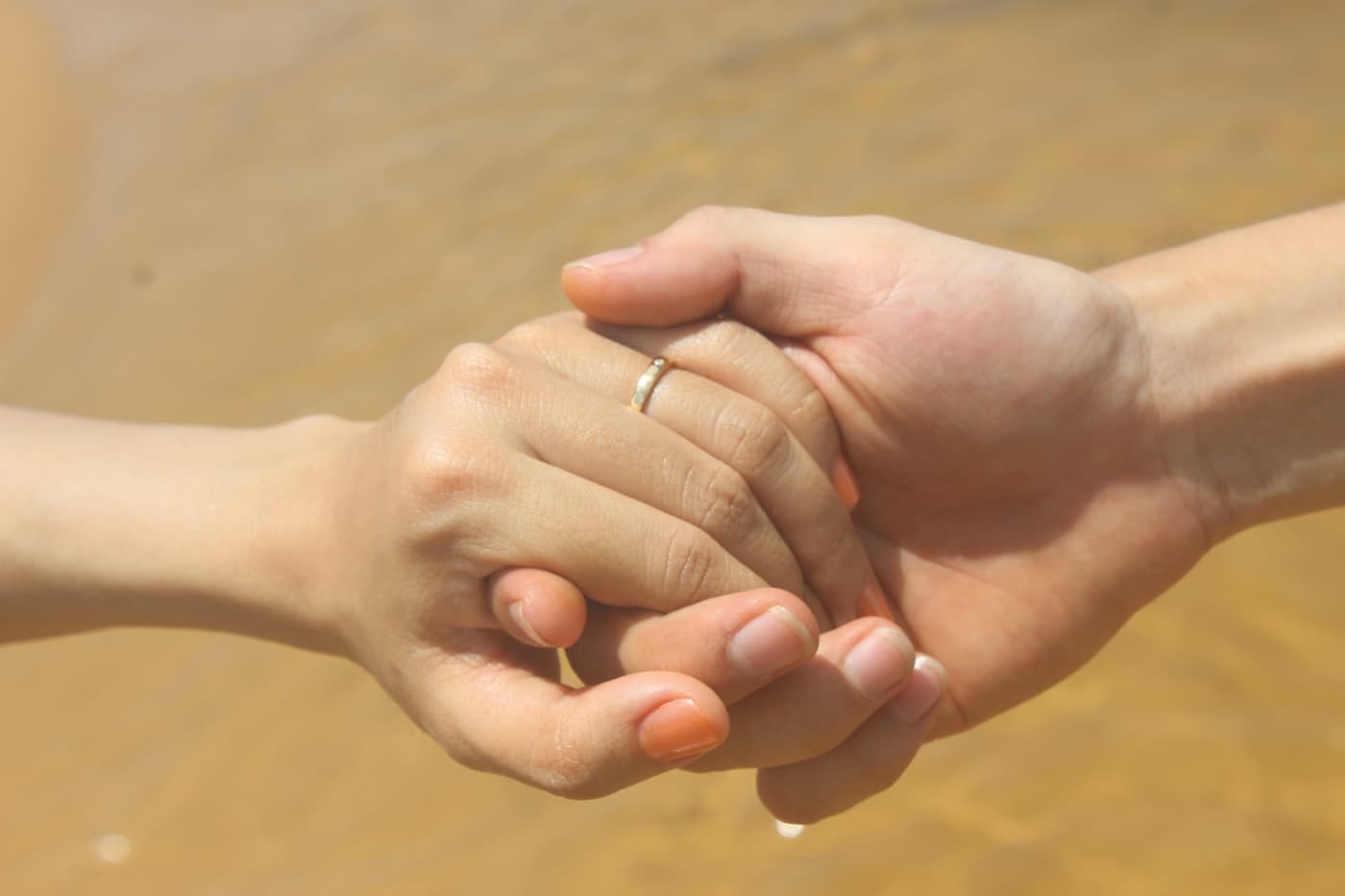 Two hands gently clasped in warm light